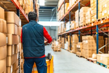 Lojistik deposunda makineli bir Latin işçinin arka görüntüsü.