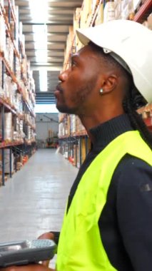 Lojistik işçisi, bir depodaki paketleri barkod okuyucusuyla tarıyor ve verimli bir envanter yönetimi sağlıyor.