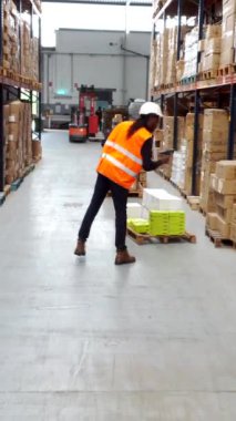 Depo çalışanları, bir dağıtım merkezinde malları etkili bir şekilde taşımak için barkod tarayıcıları ve palet krikoları kullanır.