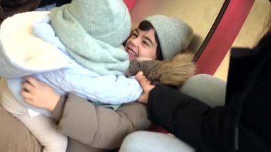 Aile üyeleri, kış tatili sırasında renkli oyun parkında birlikte gülüyor, gıdıklıyor ve oynuyorlar.