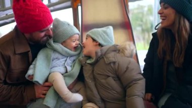 Aile birlikte keyifli anlar geçirir, oynar ve güler kar kaplı park manzarasında sıcak kışlık giysiler giyer.