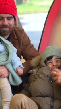Mutlu bir aile, baba ve iki oğul, bir kış günü oyun alanında birlikte vakit geçiriyorlar.