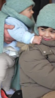 Mutlu aile, ebeveynler ve çocuklar, bir kış günü çocuk parkında birlikte kaliteli zaman geçiriyorlar.