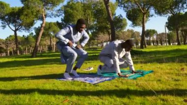 İki Senegalli adam geleneksel Dashiki kıyafetleri giyip Ramazan 'da bir parkta ibadet halısı üzerinde İslami dua ediyorlar.