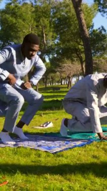Geleneksel kıyafetler giyen iki Senegalli genç adam huzur parkındaki bir kilimin üzerinde namaz kılıyor.