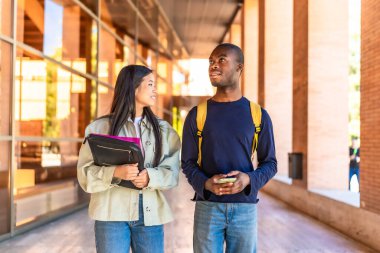 İki Afrikalı ve Çinli çok ırklı değişim öğrencisi üniversiteye yürüyerek ve konuşarak geliyorlar.