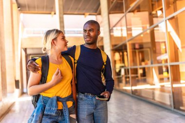Üniversite boyunca yürüyen çok ırklı Afrikalı ve beyaz bir çift.