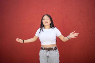 Hareketli ön portre ve kırmızı duvarın karşısında dans eden Asyalı genç bir kadının üç çeyrek boyunda.