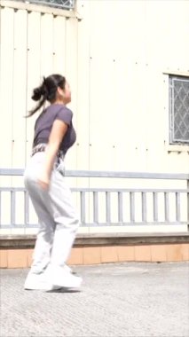 Kentte tek başına dans eden Koreli bir kadının fotokopi çekilen dikey uzunluktaki videosu.