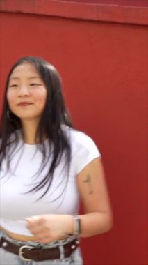 Şehirdeki kırmızı duvarın yanında tek başına dans eden Asyalı kadın modern koreografi.