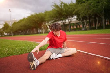 Beyaz tenli genç bir sporcunun koşmadan önce açık havada bacaklarını açması.