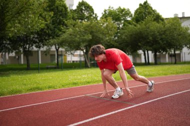 Beyaz bir gencin koşu parkurunun başlangıç çizgisinde tam uzunluğu