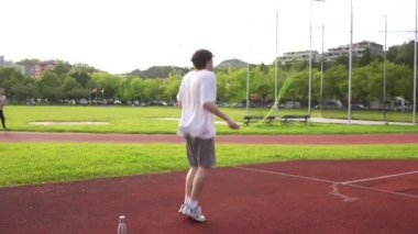 Koşu pistinde ısınmak için ip atlayan beyaz bir gencin uzun bir videosu.