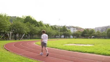 Kafkas yoğunlaştırılmış genç adam eğitimi açık hava pistinde koşuyor.