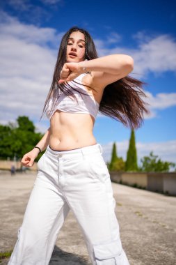 Kafkasyalı genç bir kızın parkta dans pisti dansı yaparken dikey fotoğrafı.