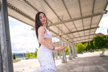 Boş bir parkta serbest stil şehir müziği yapan Kafkasyalı genç bir kadının yan görünümü