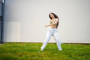 Kampüste dans eden genç bir kadının uzun bir fotoğrafı.