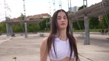 Parkta serbest dans eden beyaz elbiseli, havalı bir kadının yan görüntüsü.