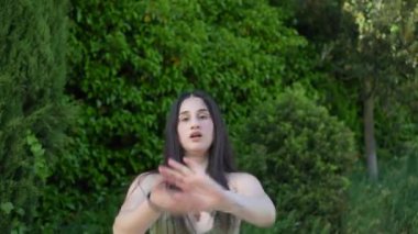 Açık bir köprüde dans eden beyaz, kendine güvenen genç bir kadının hareketli fotoğrafı.