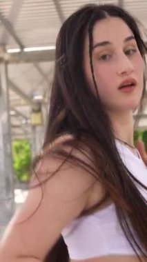 Parkta serbest dans eden beyaz elbiseli, havalı bir kadının yan görüntüsü.