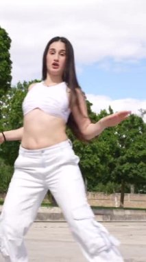 Kafkasyalı genç bir kızın parkta dans pistinde dans edişinin dikey videosu.