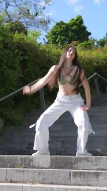 Yazlık kıyafetli genç beyaz dansçı modern şehir dansını tek başına yapıyor.