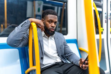 Genç işadamı metroda gidip gelirken akıllı telefonuyla meşgul oluyor, yoğun şehir yolculuğu sırasında mesajları ve uygulamaları yönlendiriyor.