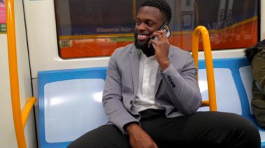 Genç profesyonel toplu taşıma araçlarında seyahat ederken keyifli bir telefon görüşmesi yapıyor.