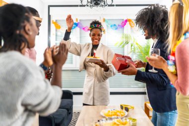 Çok ırklı genç arkadaşlar doğum günü partisinde Latin bir kadına doğum günü şarkısı söylüyorlar.