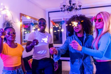 Çok ırklı arkadaşlar gece partisinde havai fişek tutarken eğleniyorlar.