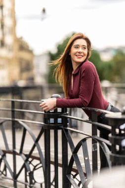 Köprü korkuluklarına yaslanan mutlu iş kadını Prag 'ın eski kasaba meydanını seyrediyor.