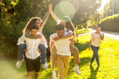 Çok ırklı arkadaşlar parkta bir araya gelip eğleniyorlar.