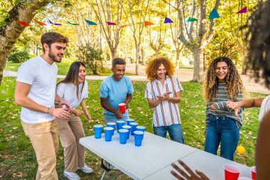 Baharda parkta bira pong oynayan çok ırklı mutlu arkadaşlar.