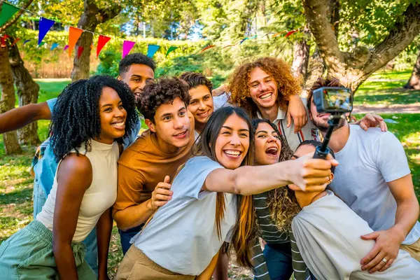 Çok ırklı mutlu genç arkadaşlar parkta doğum gününden sonra selfie çekiyorlar.