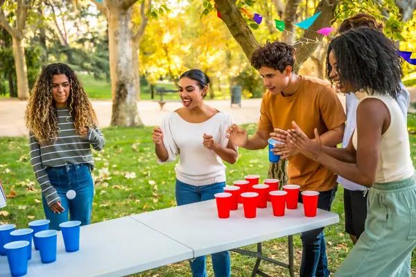 Grup pf çok ırklı milenyumlar güneşli bir bahar gününde parkta bira pong oynuyorlar.