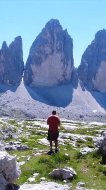 Yürüyüşçü, İtalyan dolomitlerindeki tre cime di lavaredo manzarasının tadını çıkarırken baş parmak işareti yapıyor.