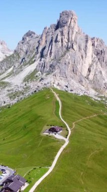 Güneşli bir yaz gününde, Passo Giau 'daki park alanının panoramik manzarası görkemli zirveleri ve bereketli manzaraları vurguluyor.