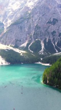 Turkuaz su ve yemyeşil ormanlar, dolomitlerde güzel bir yaz günü kayak yapan turistlerle gölün etrafını sarar.