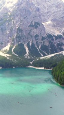 Turkuaz su ve yemyeşil ormanlar, dolomitlerde güzel bir yaz günü kayak yapan turistlerle gölün etrafını sarar.