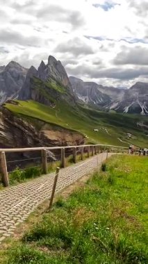 Güneşli bir yaz gününde, İtalyan dolomitlerinde Seceda dağlarının görkemli zirvelerinin altındaki yemyeşil vadilerde yürüyüş izleri.