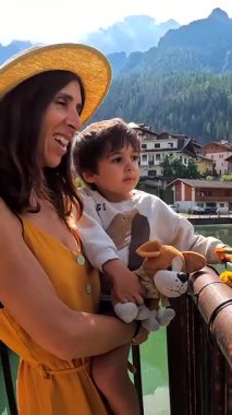 Anne, oğlunu kucağında tutuyor ve İtalya 'nın Dolomite Dağları' ndaki güzel aleghe gölü ve civetta dağ sırasının tadını çıkarıyor.