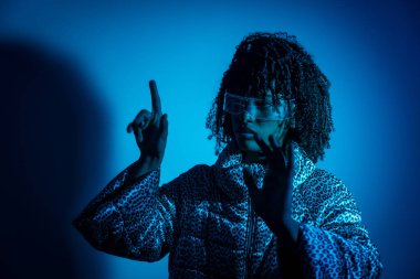 Saydam artırılmış gerçeklik gözlüğü takan bir kadın dijital holografik arayüzle etkileşime geçiyor ve sanal bir ekrana dokunuyor.