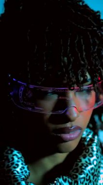 Zarif Afro-Amerikan modelleri fütüristik renkli gözlükler takarak canlı mavi stüdyo arkaplanına karşı cesur pozlar veriyorlar, çağdaş siber punk estetiğini somutlaştırıyorlar.