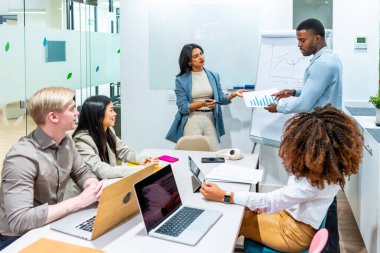 Çağdaş bir ofiste verimli bir toplantı sırasında veri analizi, grafikler ve büyüme stratejileri üzerinde işbirliği yapan iş adamları