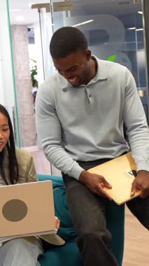 İş arkadaşları ortak çalışma alanında dizüstü bilgisayar ve ahşap tablet kullanarak bir projeyi tartışıyor.