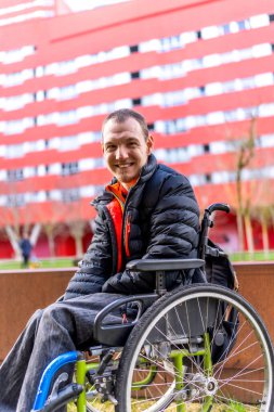 Happy man with disability sitting in wheelchair, enjoying sunny day outdoors, promoting inclusivity and positive representation of people with disabilities clipart