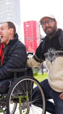 Mutlu engelli adam arkadaşlarıyla şehirde vakit geçiriyor, birbirine eşlik ediyor ve kentsel çevreden keyif alıyor.