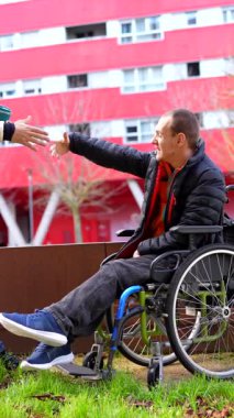 Tekerlekli sandalyedeki engelli bir adama yardım eden, arkadaşlığını ve desteğini paylaşan bir arkadaş.
