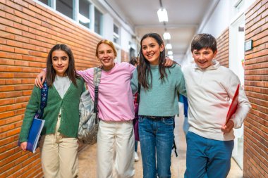 Bir grup neşeli öğrenci okul koridorunda kollarını birbirine dolamış yürüyorlar.