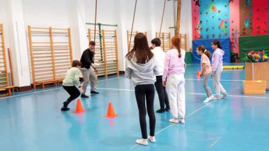 Yüksek enerjili beden eğitimi dersinde dinamik yakartop maçına katılan genç öğrenciler, okul spor salonunda takım çalışması ve rekabetçi ruh sergilediler.